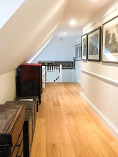 an empty room with wooden floors and pictures on the wall above it, along with other furniture