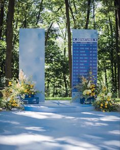 a blue sign sitting in the middle of a forest filled with lots of trees and flowers