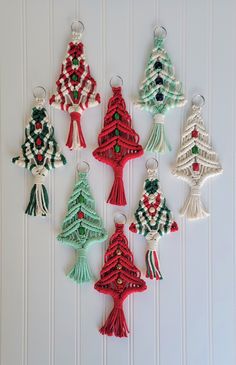 christmas tree ornaments are hanging on a white wall with bead trimmings and tassels