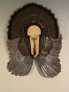 a turkey mask mounted to the wall with feathers on it's face and an antler