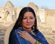 a woman wearing a blue scarf standing in front of an old building