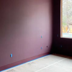 an empty room with purple walls and blue tape on the floor in front of it