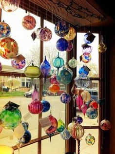 many colorful glass ornaments hanging from a window