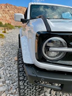 the front end of a silver truck parked on rocks