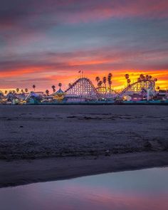 an amusement park at sunset with roller coasters in the background