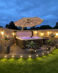 an outdoor hot tub surrounded by potted plants and lit up lights on the deck