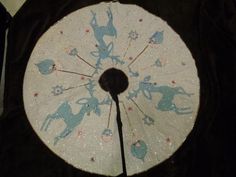 a white and blue hand fan with silhouettes of people on the front, sitting on a black surface