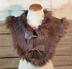 This mantle or shoulder cover has been made with split leather and synthetic fur around the edges. Inspired by shaman or warlock, druid, viking or tribal style characters, this garment can be worn in combination with a cloak, over or under it. It is an accessory to protect yourself from the elements, with a soft fur finish and a front lace-up closure. Warrior, explorer, archer or shaman, this suede garment is the piece you need to complete your outfit. Nice, warm and very cool! Add this piece to Werewolf Aesthetic, Medieval Cosplay, Viking Armor, Viking Costume, Larp Armor, Fur Cape, Leather Armor, Fur Clothing, Period Costumes