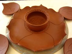 a clay pot with leaves on it sitting on top of a white table next to other items