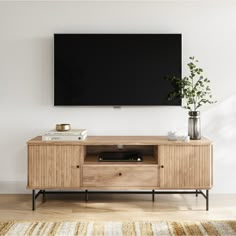 an entertainment center with a television mounted on the wall and plants in vases next to it