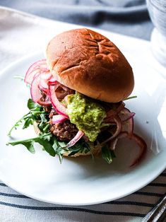 a white plate topped with a sandwich and veggies on top of lettuce