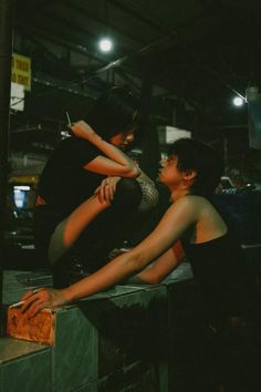 two people sitting next to each other on top of a wooden box in a warehouse