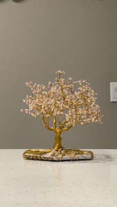 a gold tree sculpture sitting on top of a white countertop next to a light switch