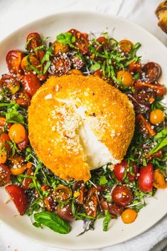 a white plate topped with a piece of bread covered in cheese surrounded by lots of vegetables