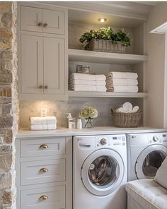 a washer and dryer sitting in a room next to each other with towels on the shelves