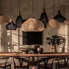 a wooden table topped with vases and plants next to a wall covered in hanging lights