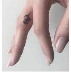 a person's hand with a small flower tattoo on their left thumb and finger