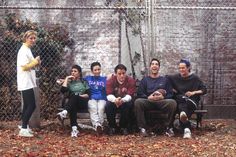 a group of people sitting on a bench in front of a chain - link fence