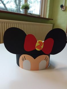 a mickey mouse head with a red bow on it's head, sitting on top of a table