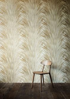 a chair sitting on top of a wooden floor next to a wall with a plant pattern