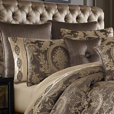 a bed covered in brown and tan comforters with pillows on top of it's headboard