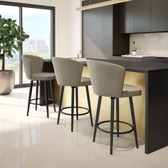 a kitchen with three bar stools next to a counter and a potted plant