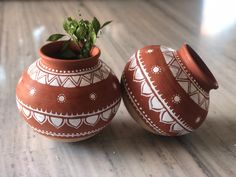 two brown and white vases sitting on top of a wooden table next to each other