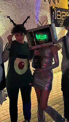 three people dressed up in costumes and one is holding an old fashioned computer screen with the word'alien'on it