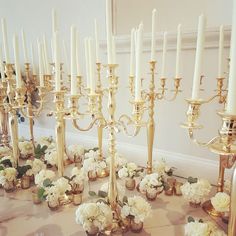 a table topped with lots of white flowers and gold candelabra filled with candles