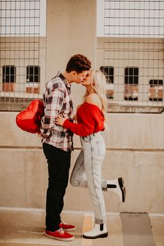 a man and woman kissing while standing next to each other in front of a building