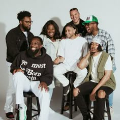 a group of people sitting around each other posing for a photo with one man in the middle