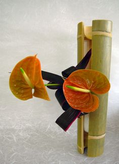 a flower that is sitting on top of a bamboo pole in front of a white background