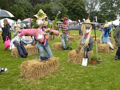 several scarecrows are standing on hay bales in a field with people dressed as scarecrows