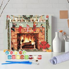 a fireplace decorated with stockings and stockings on it, surrounded by paintbrushes and other crafting supplies