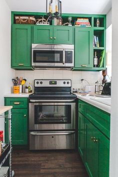 a kitchen with green cabinets and stainless steel stove top oven in the middle of the room