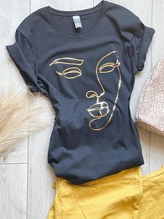 Description 100% cotton t-shirt. Black shirt with graphic outlined in gold. True to size. Sizes Women (S-XL) Neckline Options:  Crew or V-neck Processing This product will be created and shipped within 5-7 business days. Be sure to check out my other creations at www.canvasandcreationsus.etsy.com Trendy Gold T-shirt For Summer, Trendy Gold Summer T-shirt, Gold Graphic Tee With Crew Neck, Trendy Gold Crew Neck T-shirt, Gold Short Sleeve Tops With Graphic Print, Gold Graphic Print Short Sleeve Top, Trendy Gold Cotton T-shirt, Gold Crew Neck Cotton Top, Gold Cotton Crew Neck Top