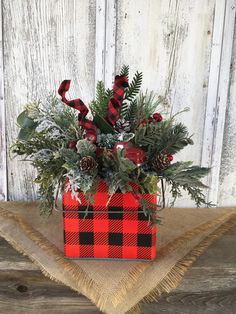 a red and black plaid box with greenery in it