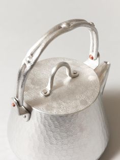 a silver tea kettle sitting on top of a white table