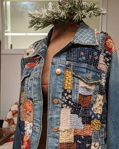 a denim jacket with patches and buttons on the back, hanging from a mannequin's head