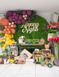 an arrangement of flowers and fruit on display in front of a sign that says aluna nights