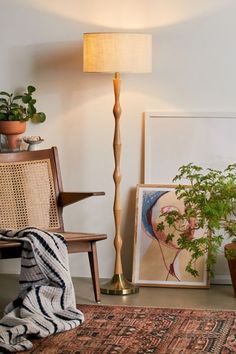 a lamp that is on top of a wooden table next to a chair and potted plant