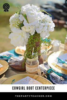 there is a vase with white flowers in it on top of a table that has plates and napkins around it