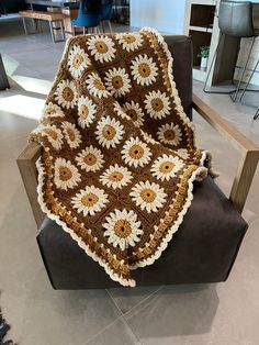 a crocheted sunflower blanket sitting on top of a chair in a room