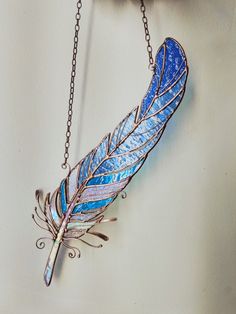 a blue feather is hanging from a chain