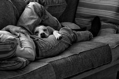 a man laying on top of a couch next to a dog