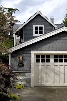 a gray house with two white garage doors and three different color swatches on it