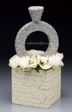 a small box with flowers and a ring on the top that has words written all over it