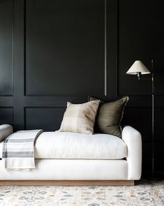 a living room with black walls and white couches in the corner, two lamps on either side