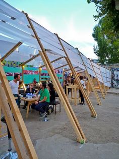 several people sitting at tables under wooden structures