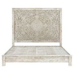 a white wooden bed with intricate carvings on the headboard